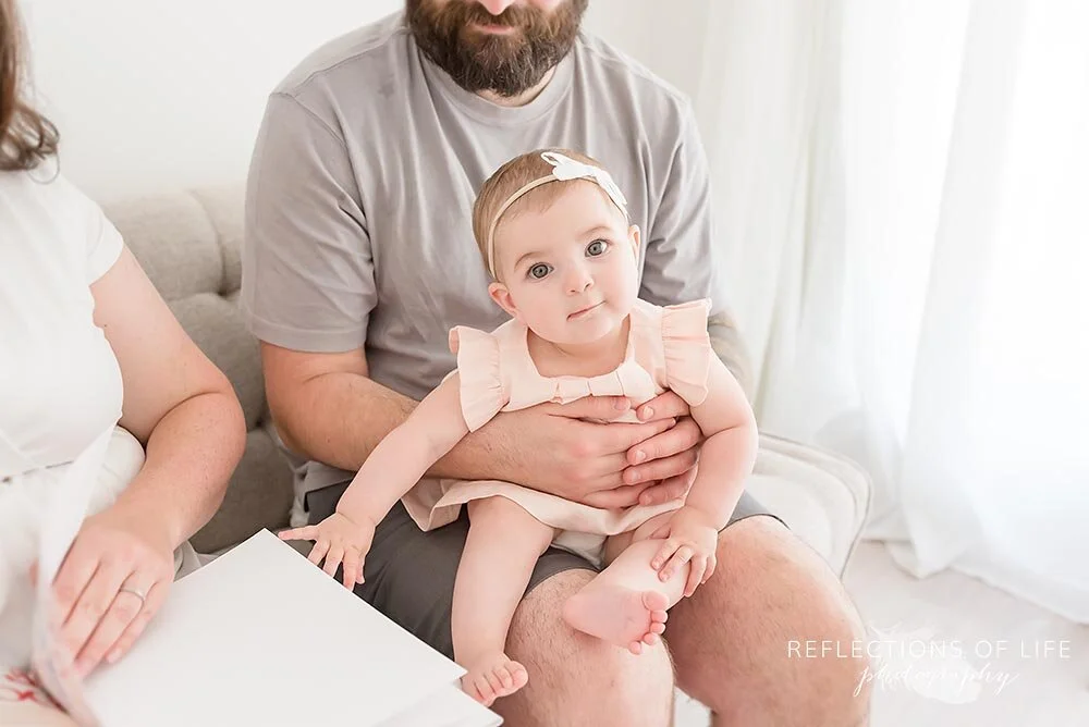 Little baby girl sitting on daddys lap in Grimsby Photo Studio