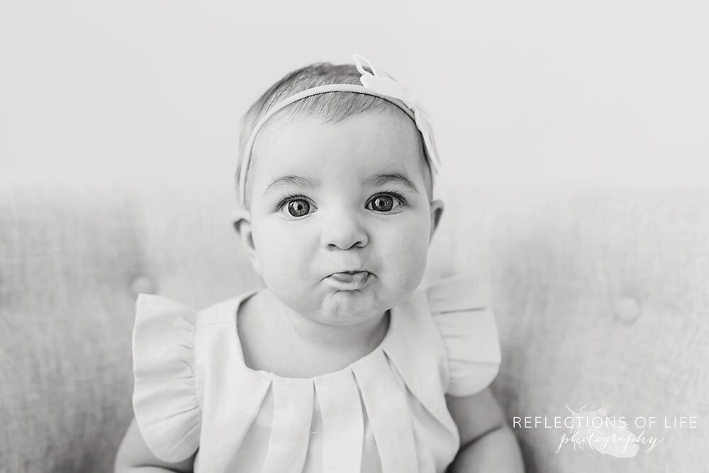 Little baby girl making super cute face at the camera Professional baby photographer Niagara