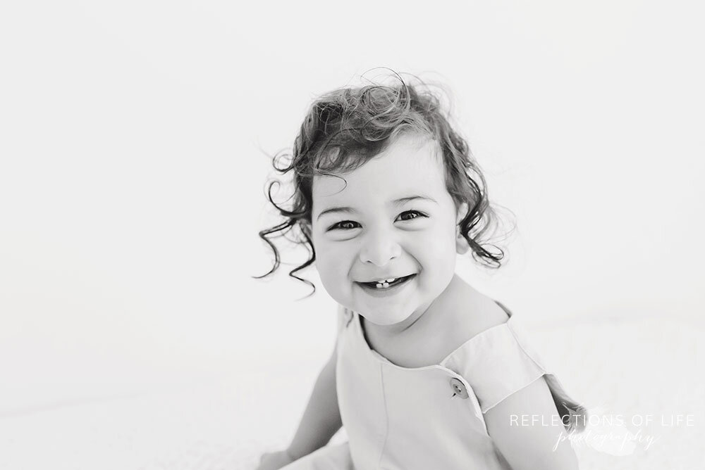 Adorable little boy smiling at the camera in black and white in beba bean romper Grimsby Ontario Professional Photography