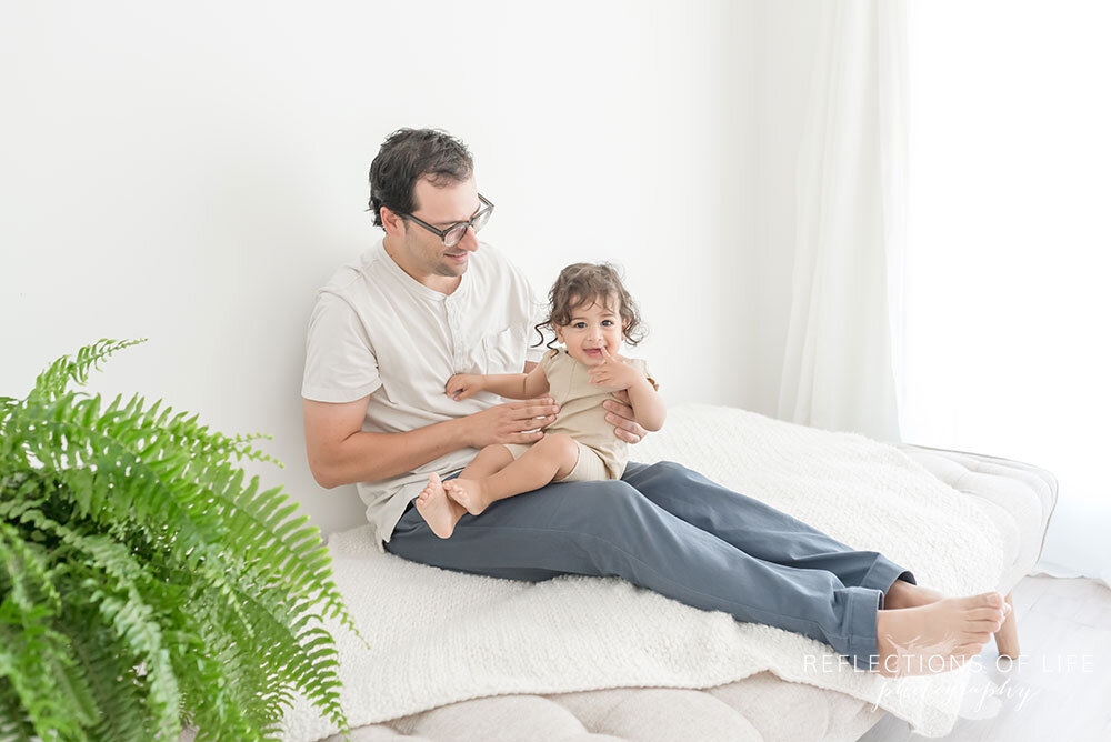 Niagara Family photographer of baby boy and his dad on neutral couch in natural light studio