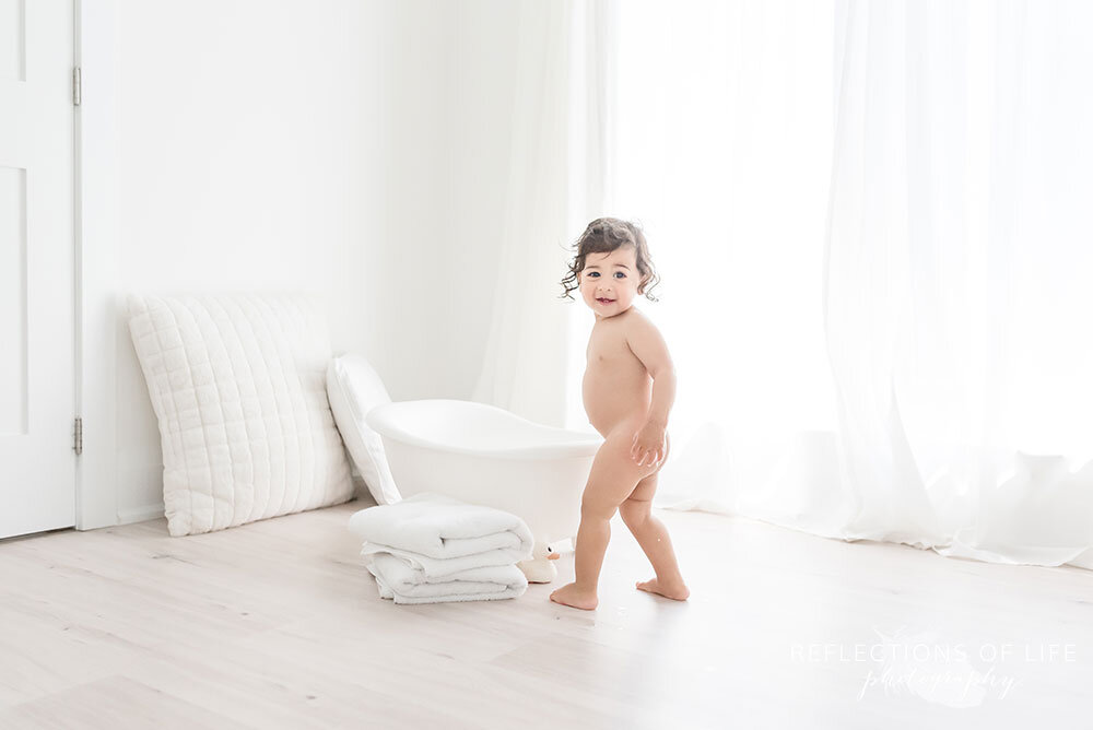 Baby boy about to jump in the tiny bathtub in Natural light studio Grimsby Ontario Canada