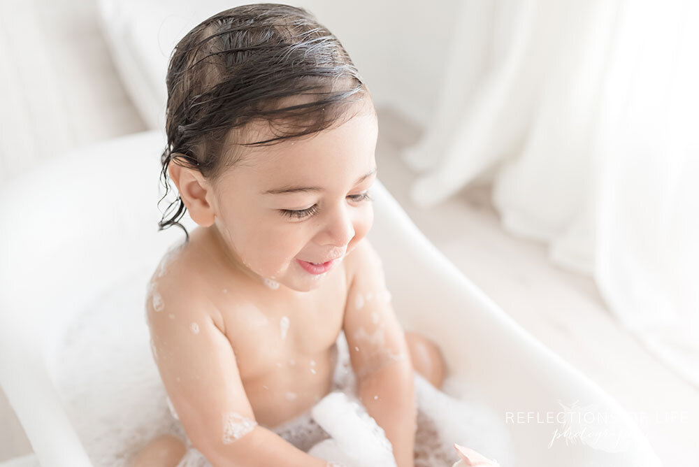 Little boy playing in the water in tiny bathtub Niagara Region baby and family photographer