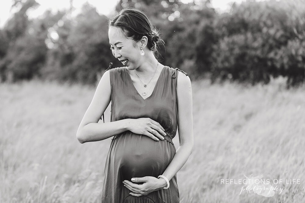 Beautiful black and white photo of mama with her hands on her belly smiling Niagara Pregnancy Photographer