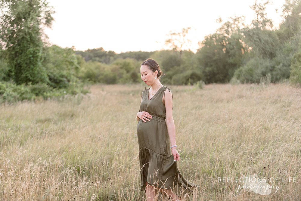 Expecting mama walking through the field holding her dress at sunset Grimsby Pregnancy Photographer