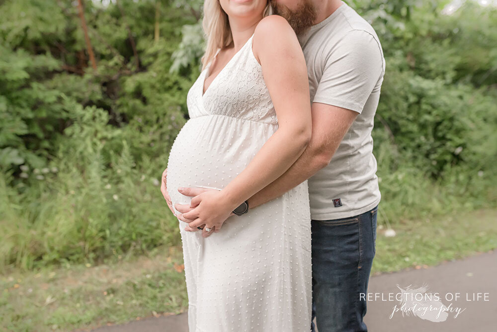 Cute pregnancy pictures with mom and dad outdoors on a path near trees in Grimsby Ontario Canada