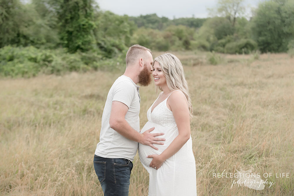 Husband whispers into his pregnant wife's ear Grimsby Ontario Maternity Photographer
