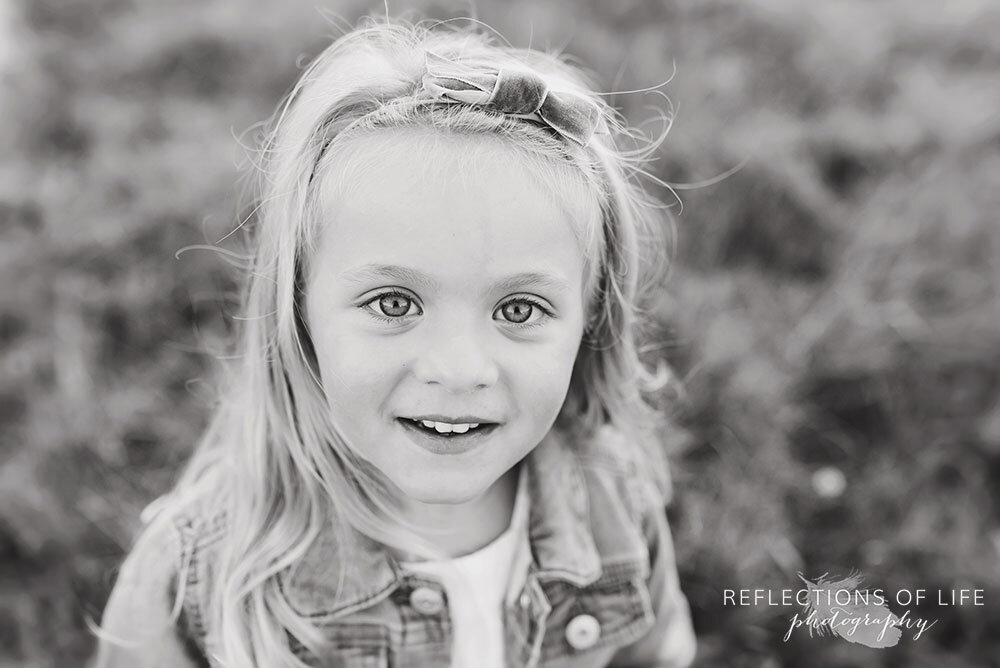 Adorable image of little girl in jean jacket looking into the camera lens in black and white