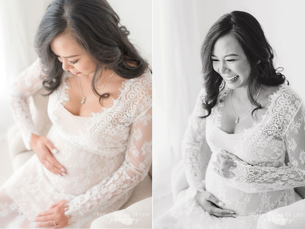 Gorgeous mama with white lace gown looking down at her baby belly and laughing
