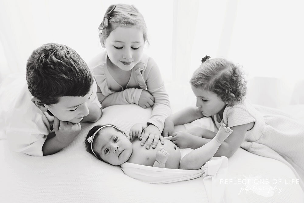 Newborn baby girl awake and looking at the camera surrounded by her siblings Niagara Ontario