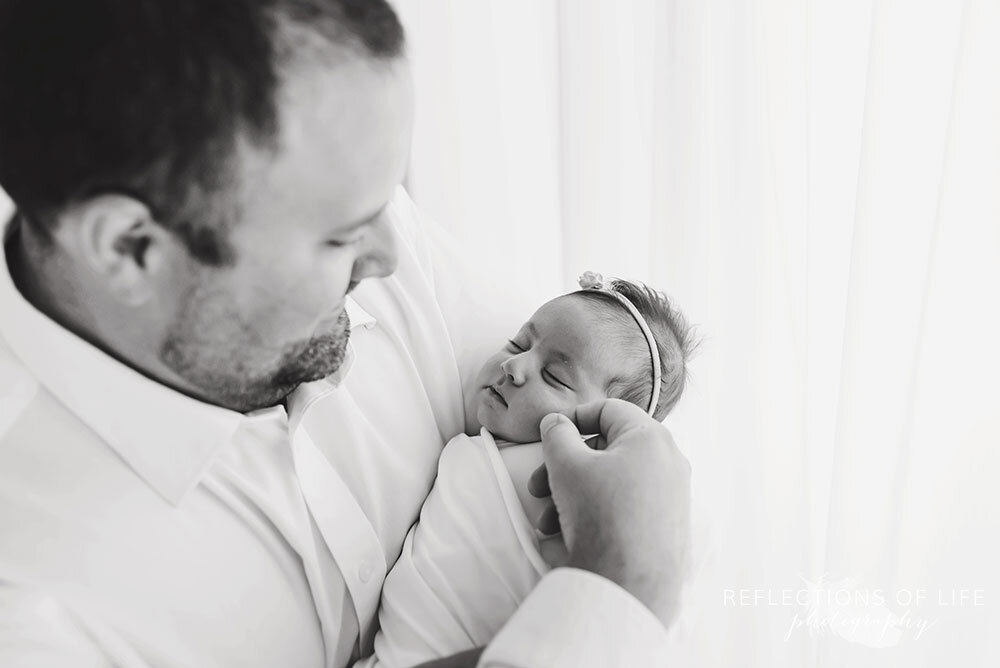 Daddy holding his newborn baby daughter in Niagara Region professional photographer