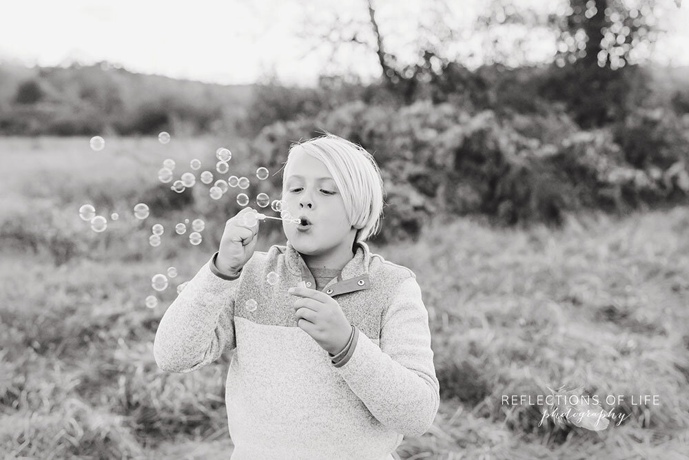 Little boy blowing bubbles in open field Niagara Ontario