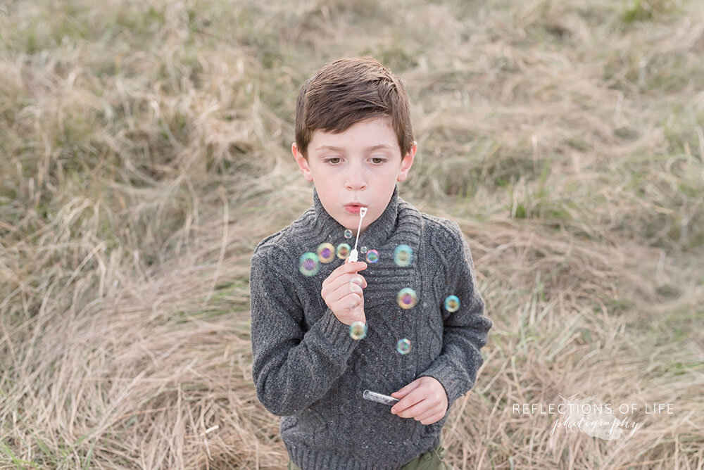 Boy blowing bubbles during a family photo session in Niagara Ontario