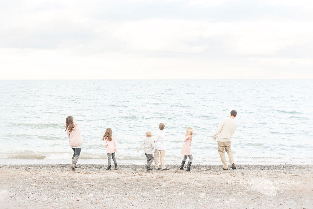 Family throwing rocks into Lake Ontario Niagara Region family photographer