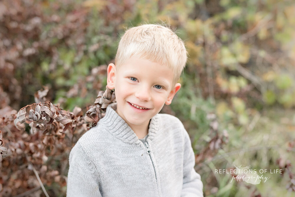 Little boy smiling at the camera during field photoshoot in Niagara Region Ontario
