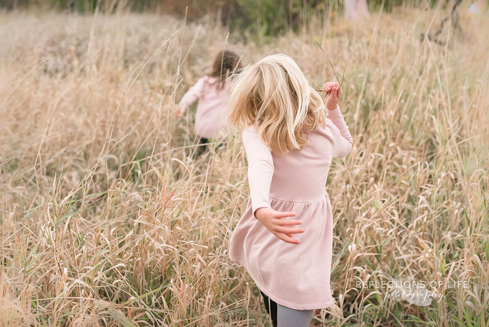 Daughters running though an open field in Niagara Region