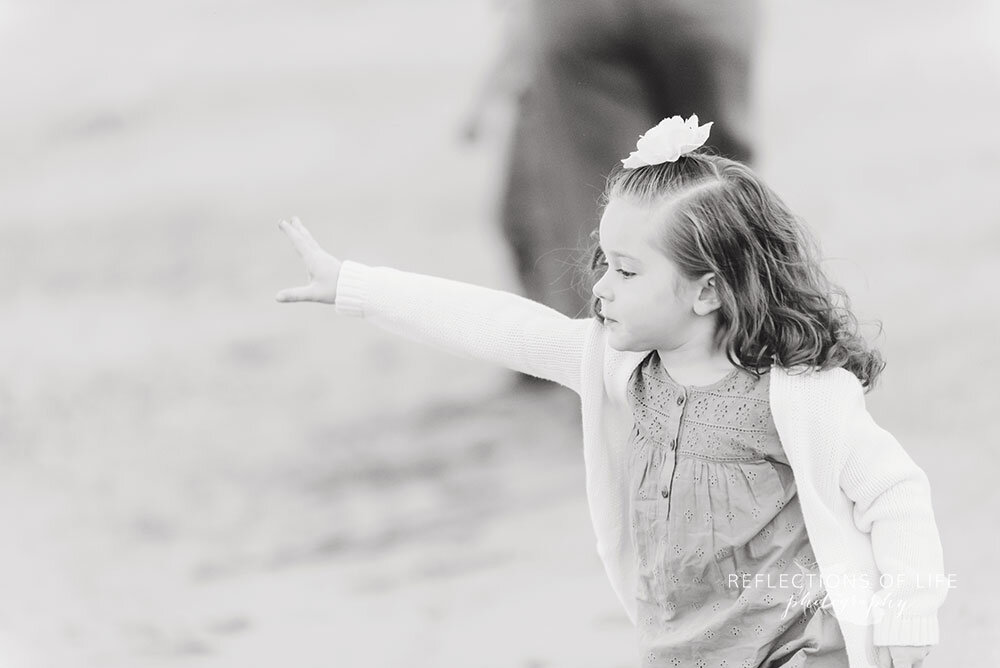 Black and white image of little girl playing on Casablanca beach during family photoshoot in Grimsby Ontario