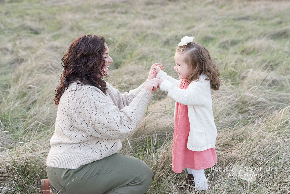 Mother and daughter play pat-a-cake during family photos in Grimsby Ontario field