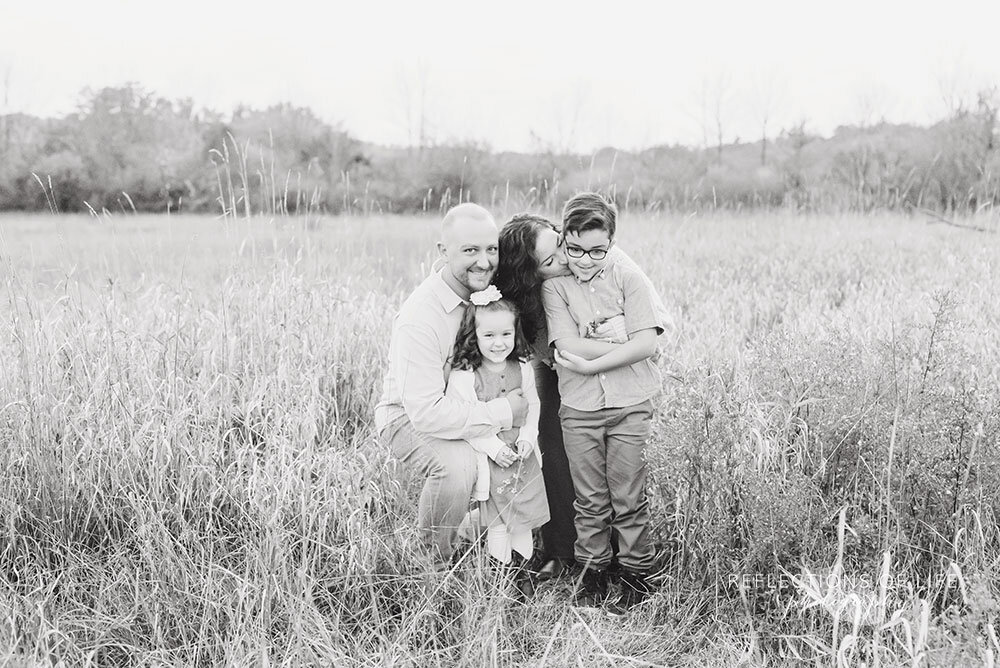 Family snuggles together and gives kisses during family photoshoot in Niagara Region
