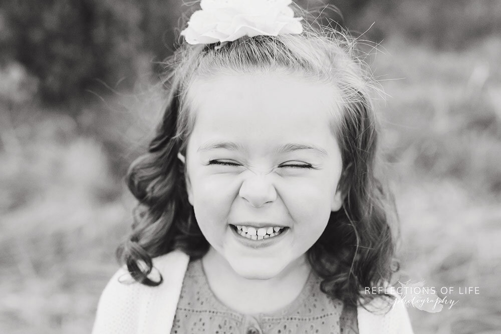 Little girl smilies with a huge scrunchy nose in black and white Grimsby family photographer
