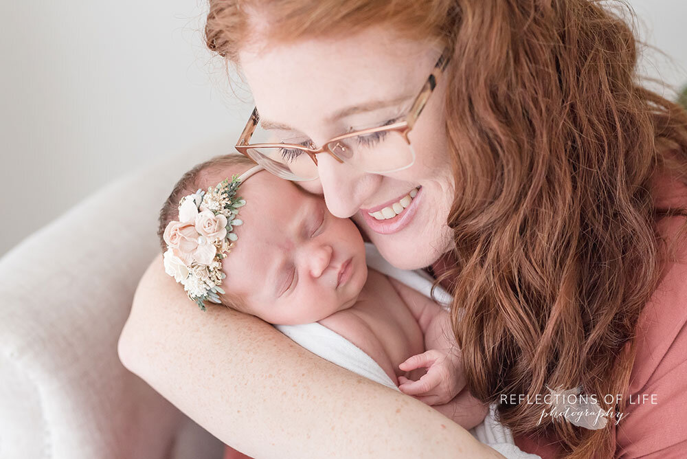 Newborn baby girl in her mamas arms redhead with with floral headband by Sweet Nest Boutique