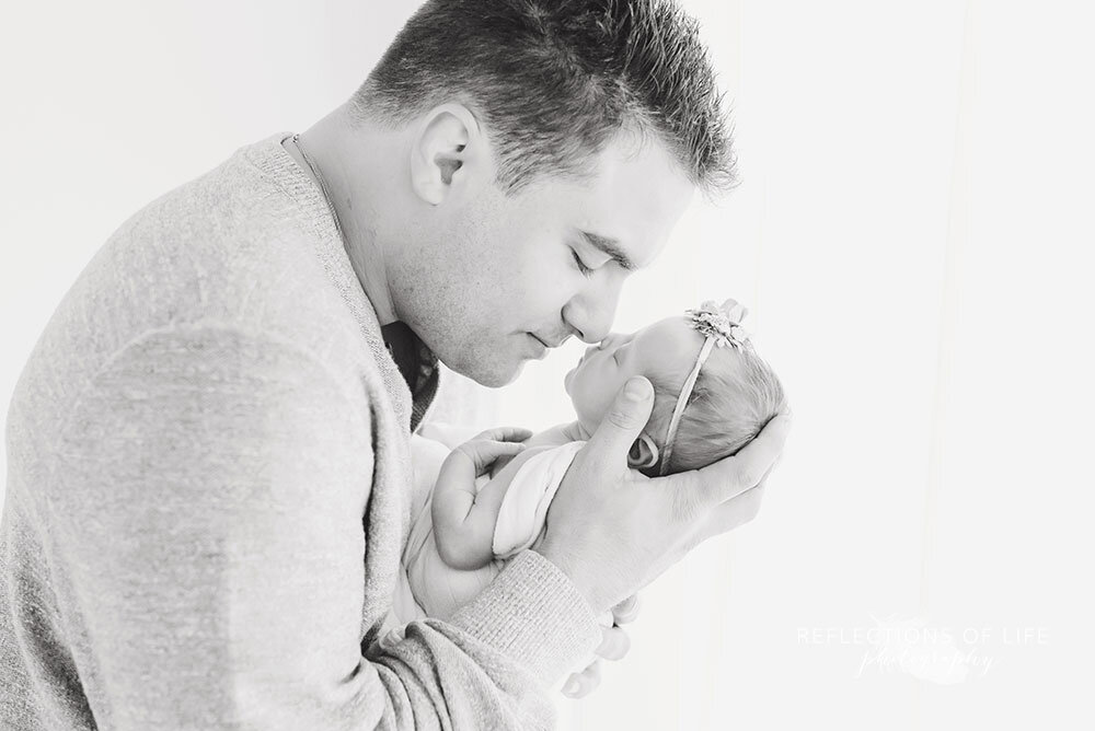 Black and white image of newborn baby girl rubbing noses with her daddy at Niagara Region photo studio