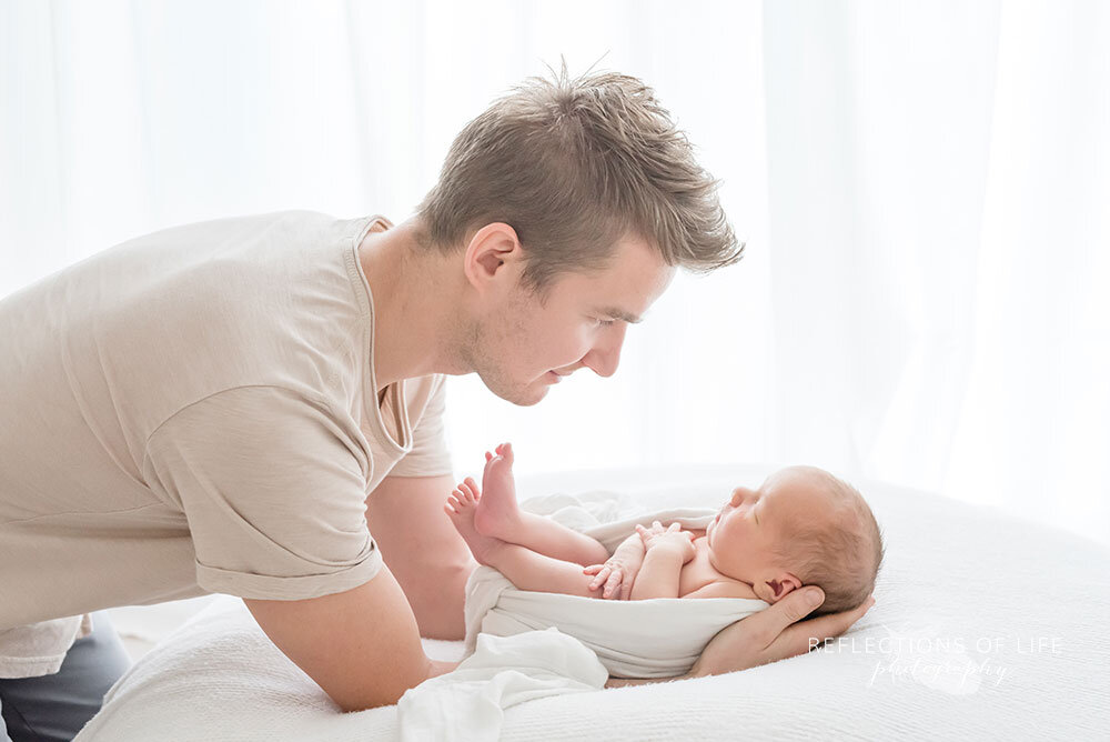 New dad looks down at new born baby boy Niagara Region Professional Photographer