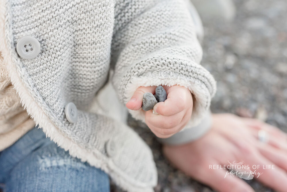 Baby girl holding rocks in her hand during family photo session in Niagara Region of Ontario Canada
