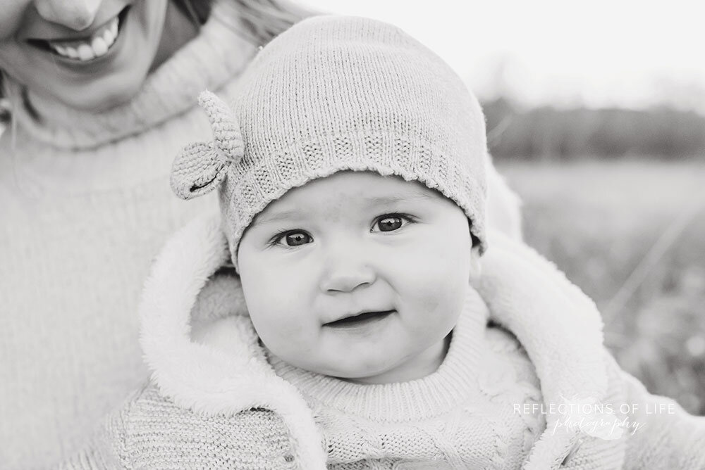 Little girl smiling at the camera in knit hat black and white Niagara Region professional photographer