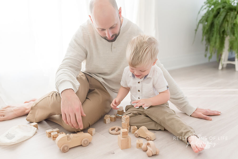 Father and son play with wooden toys on floor at niagara family photography studio