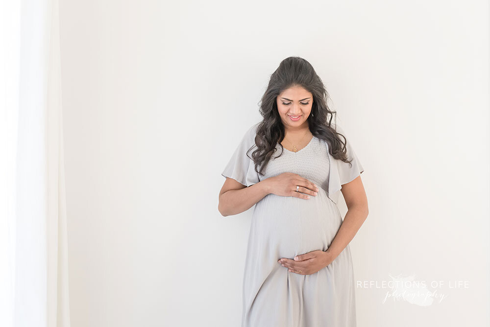 Pregnant woman holds hands on belly niagara maternity photoshoot