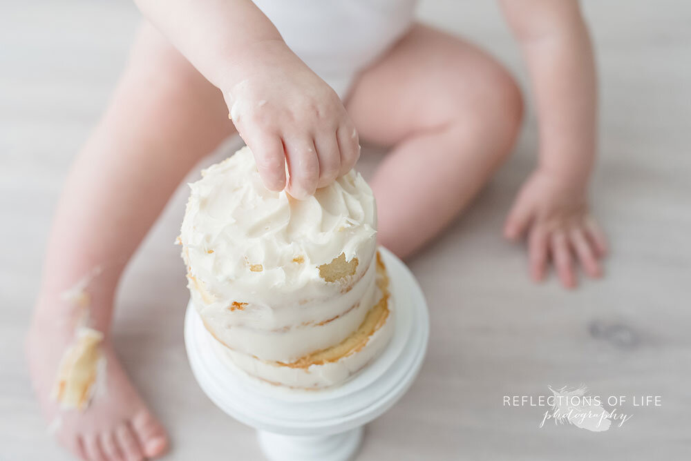 Baby's hands in birthday cake
