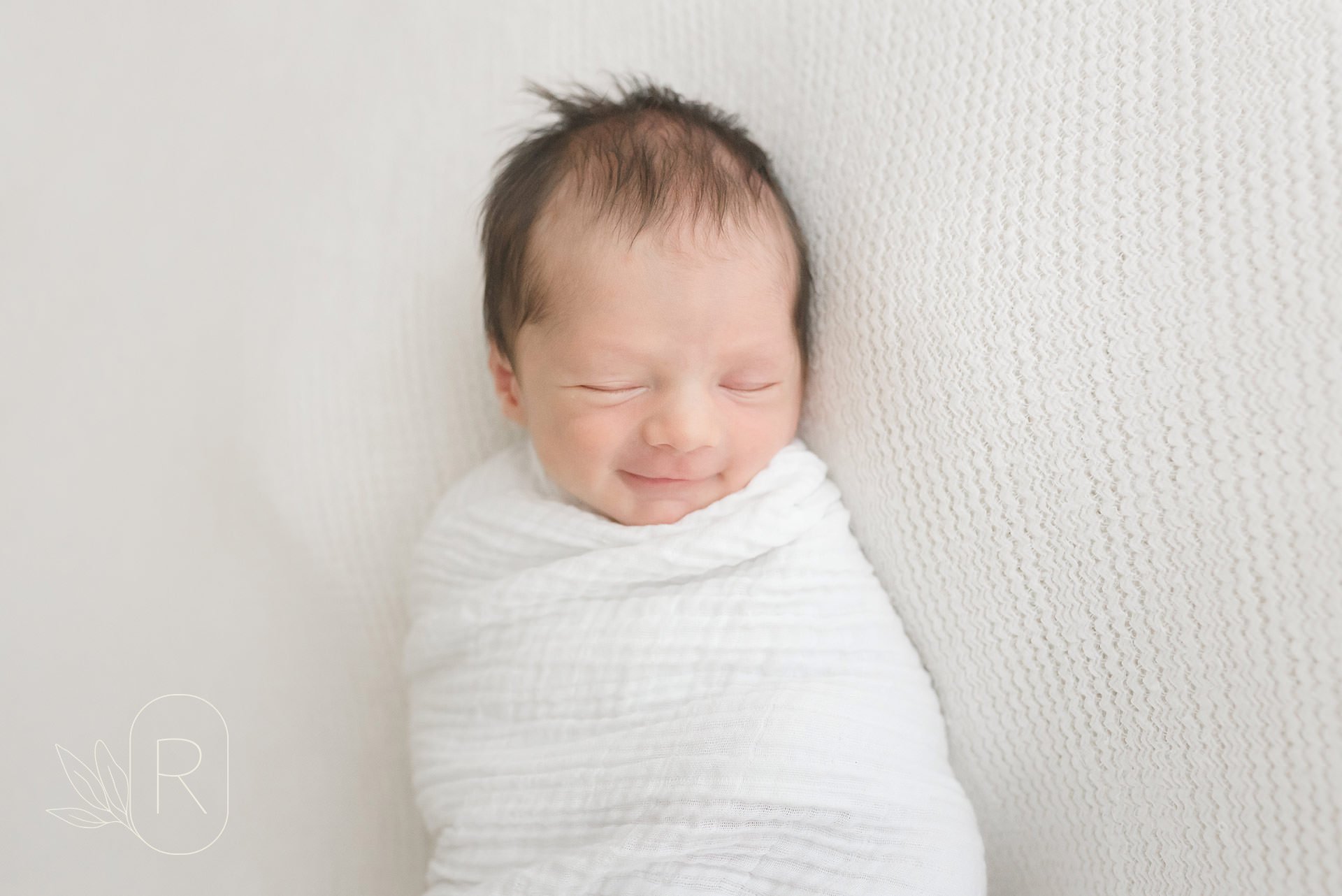 swaddled-newborn-smiling-book-early-reflections-family-photographer-niagara-ontario.jpg