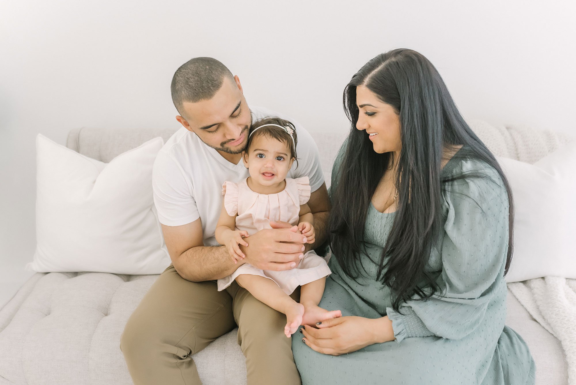 Adorable young family sitting on couch in natural light studio (Copy)