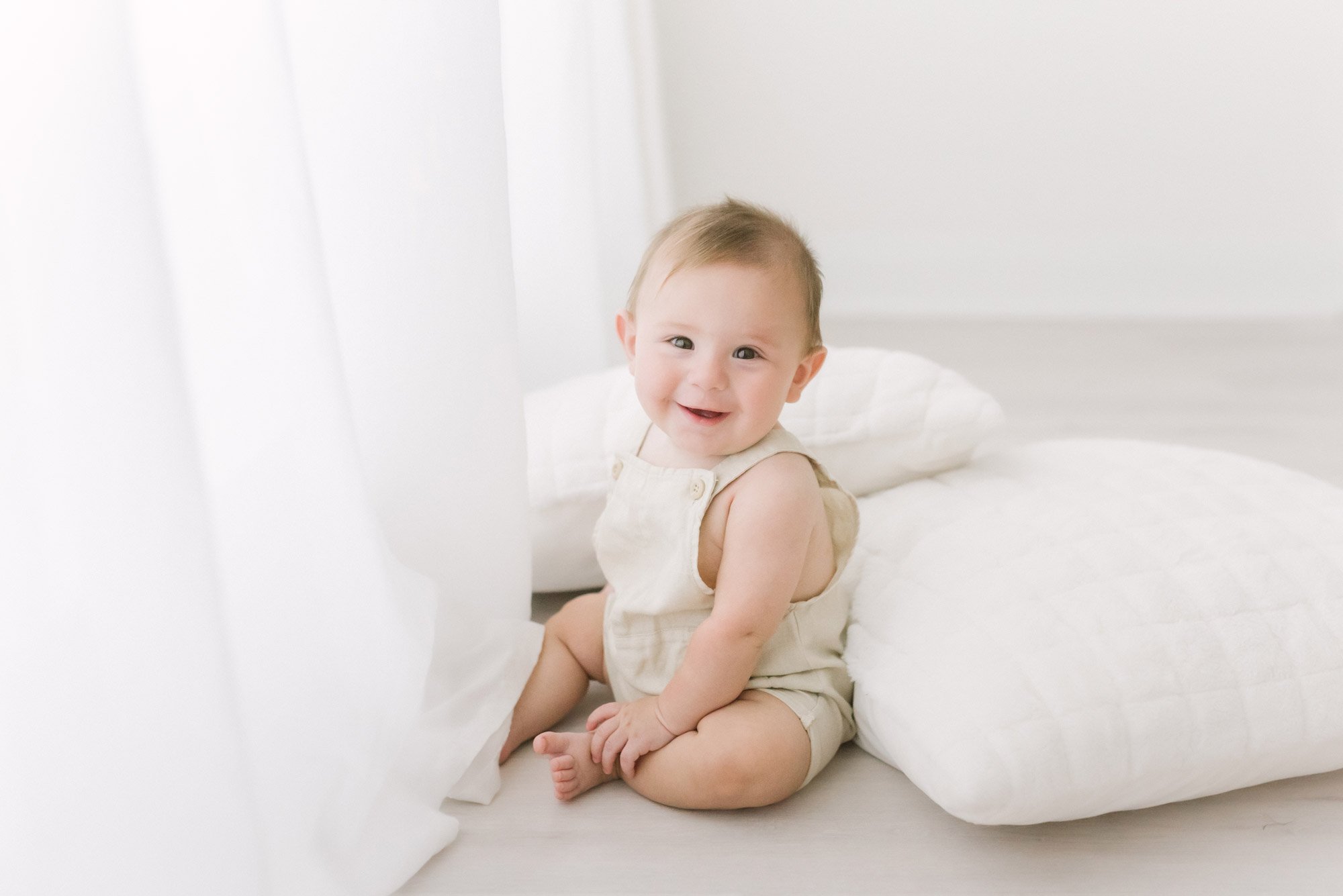 Adorable baby boy sitting on the floor near the curtains