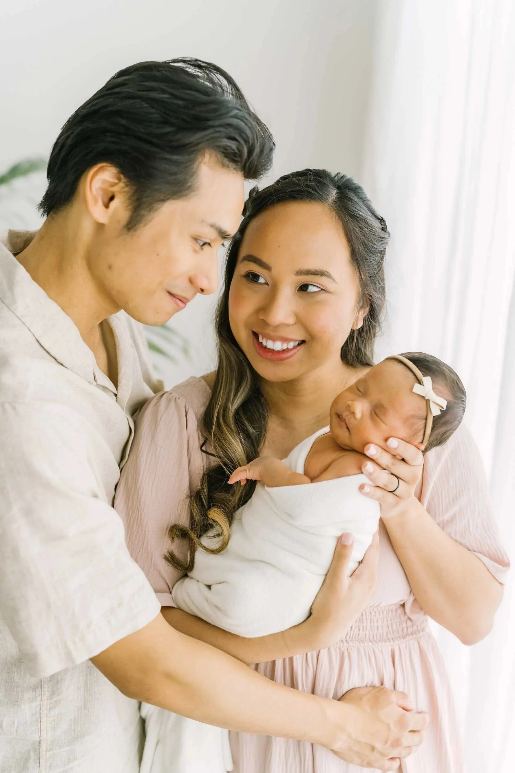Parents looking at their newborn baby posing for newborn photography in Hamilton Ontario​ studio by Reflections