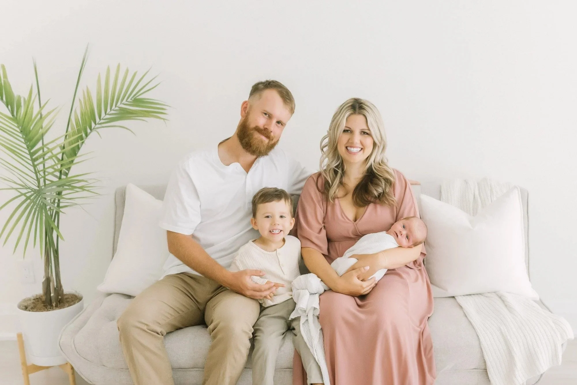 Family sitting on bed captured by Hamilton Newborn Photographer at studio by Reflections