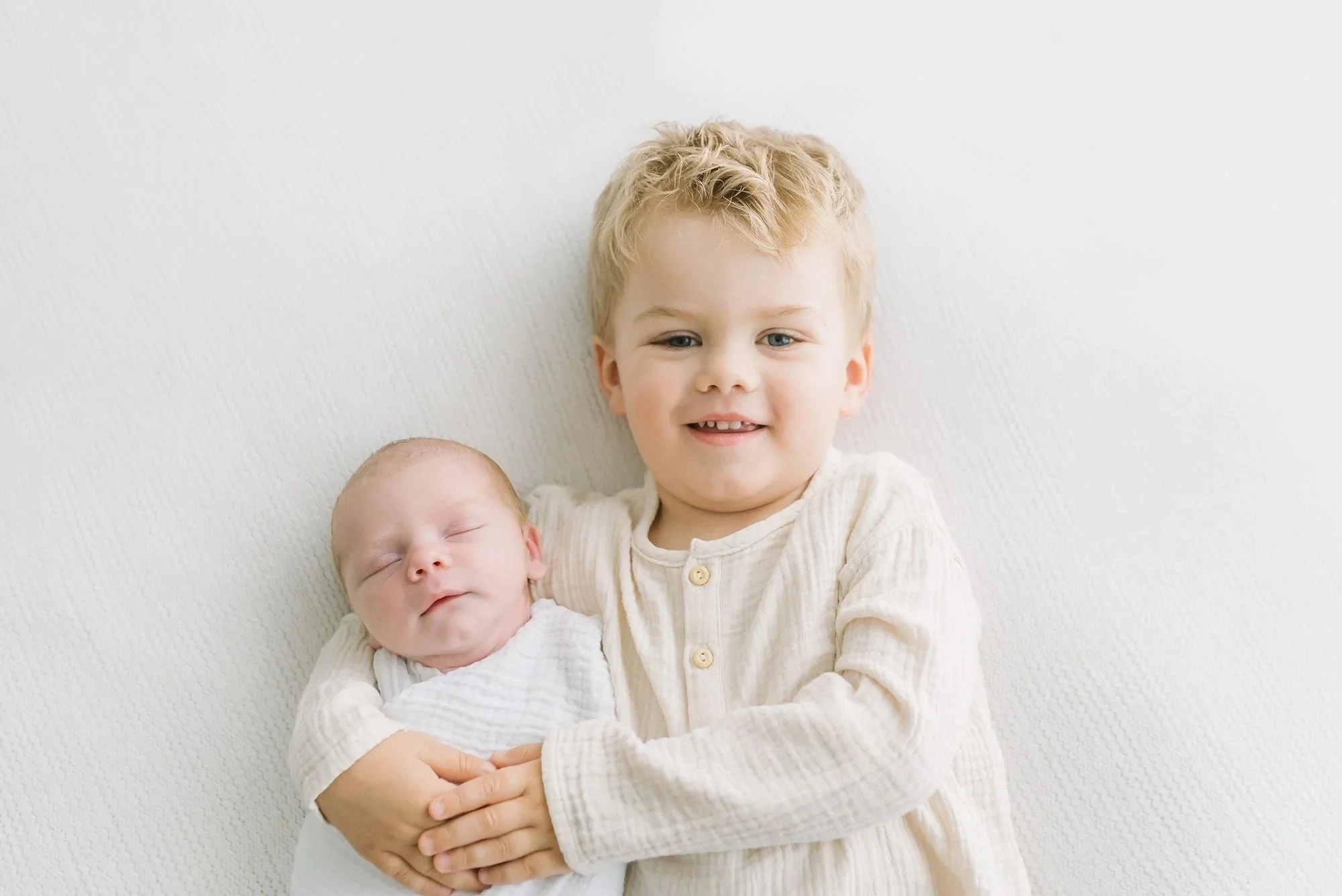 Older sibling holding newborn in a photography studio in Hamilton. 