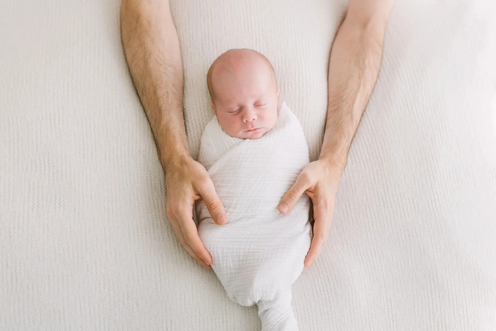 Dad holding newborn in a photography studio in Hamilton. 