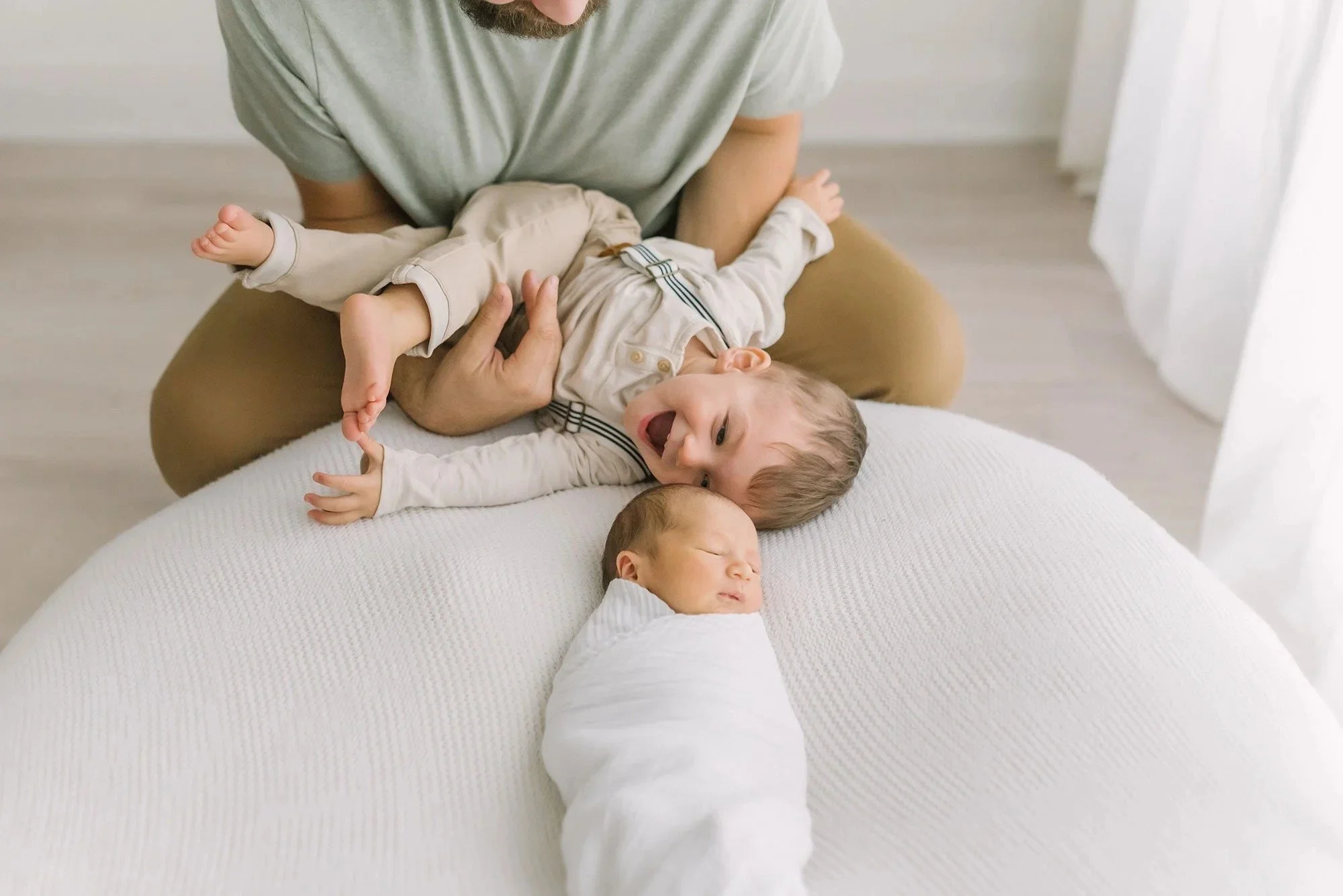 Dad holding son and looking at newborn in a photography studio in Hamilton. 