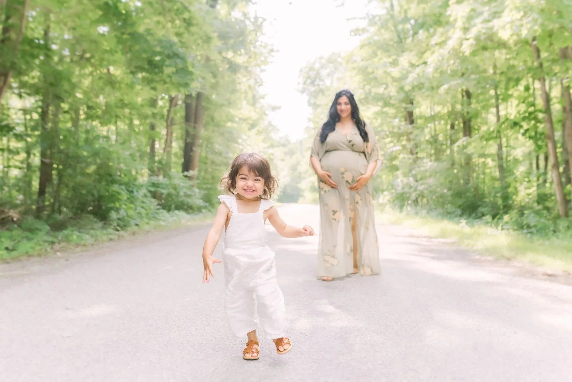 Maternity photography in Niagara, Ontario with a child playing in front of expecting mom