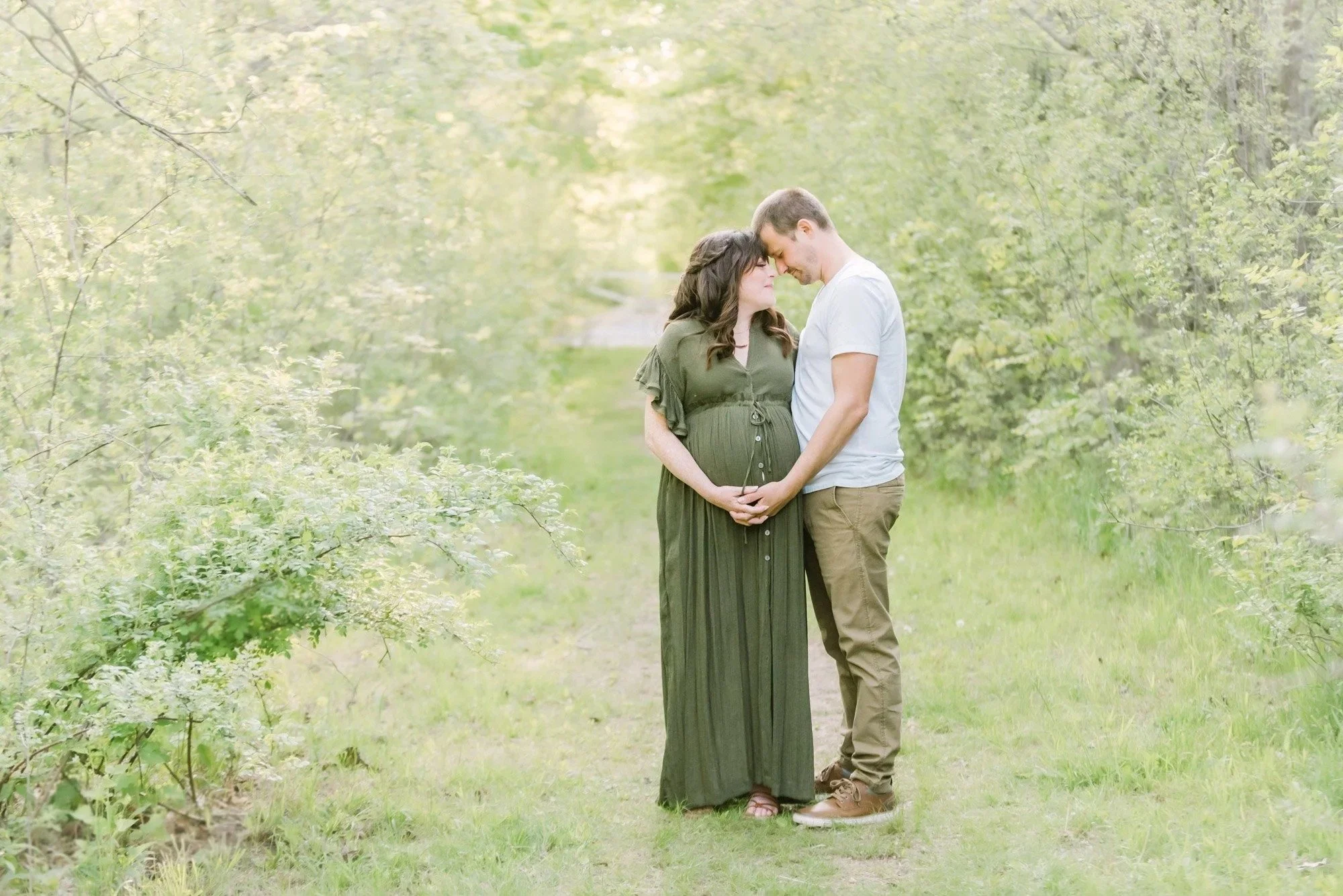 Maternity photography in Niagara, Ontario with a couple posing amongst greenery