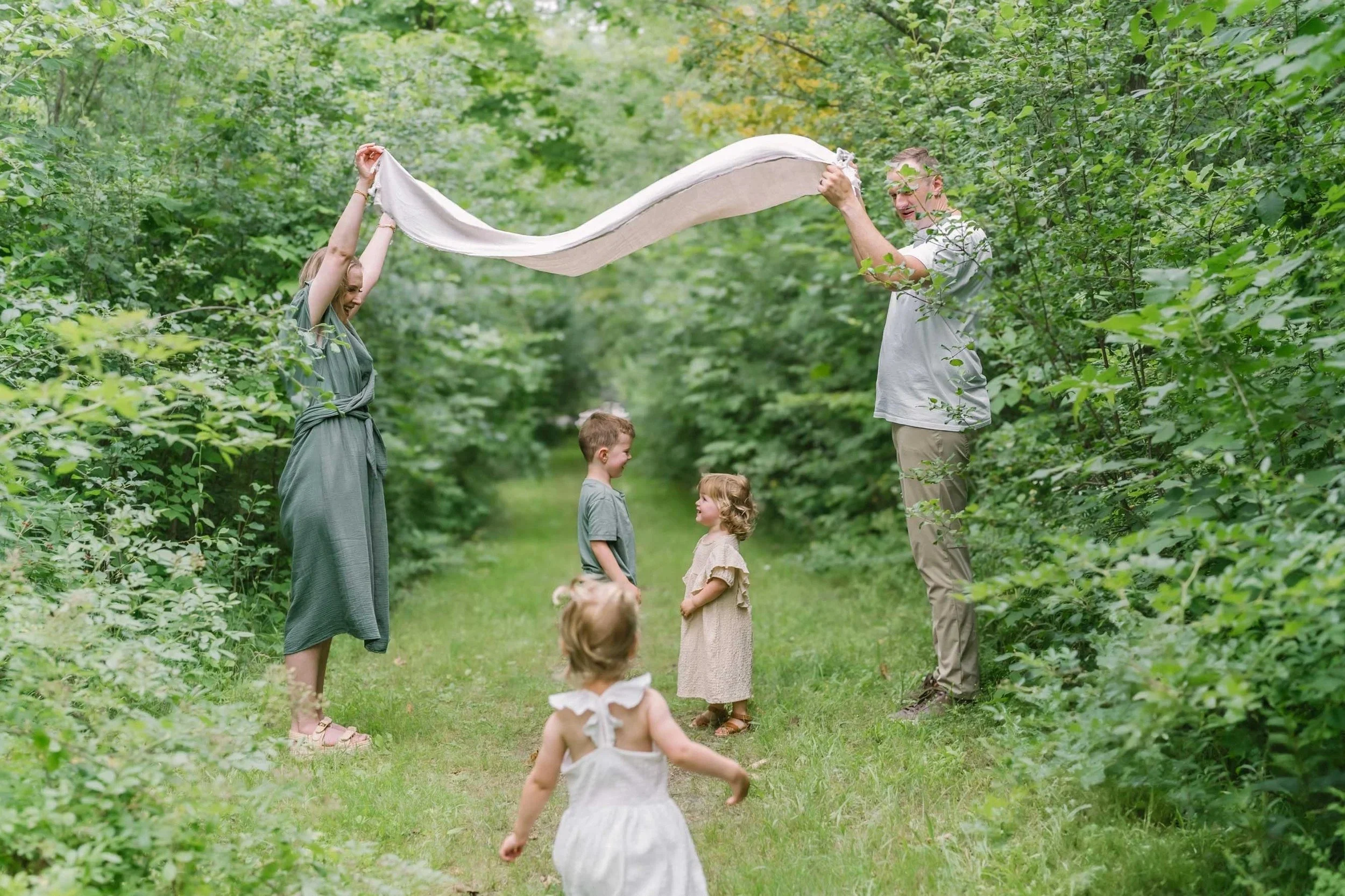Family playing together in a forest captured by Niagara family photographer, Reflections Photography