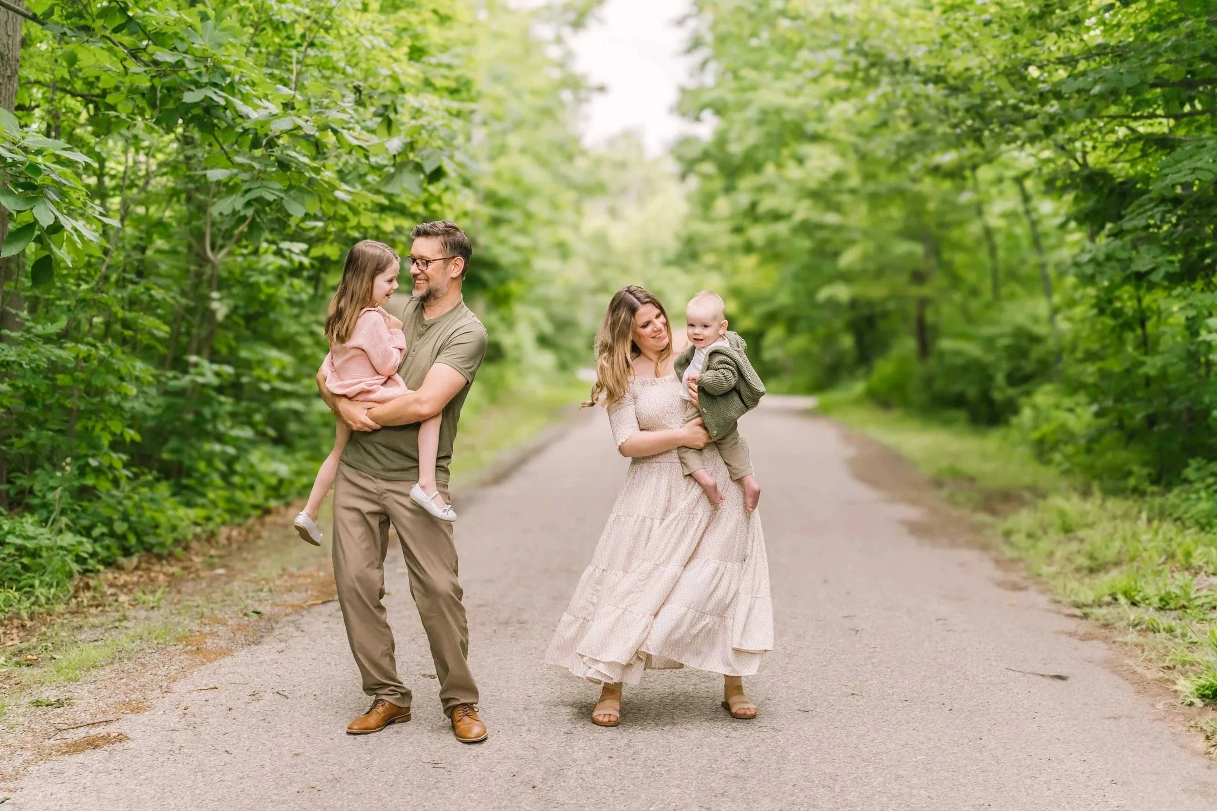 Family playing on a path in a forest captured by Niagara family photographer, Reflections Photography