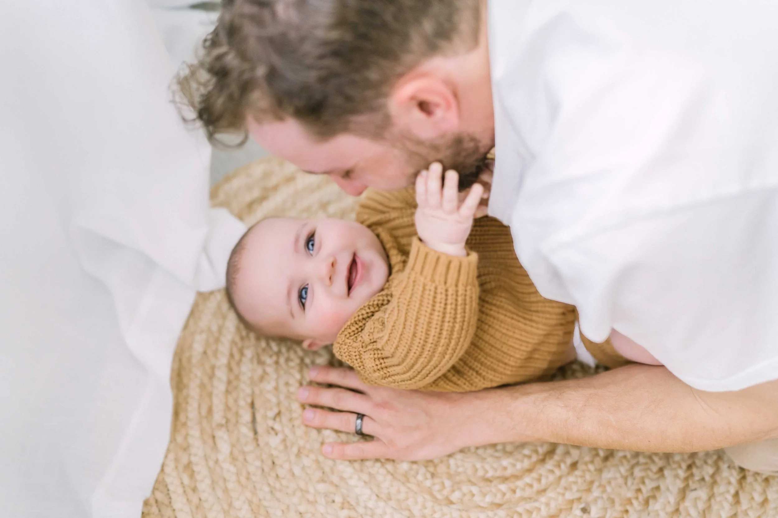 Baby reaching for father's face with a bright smile in photography studio