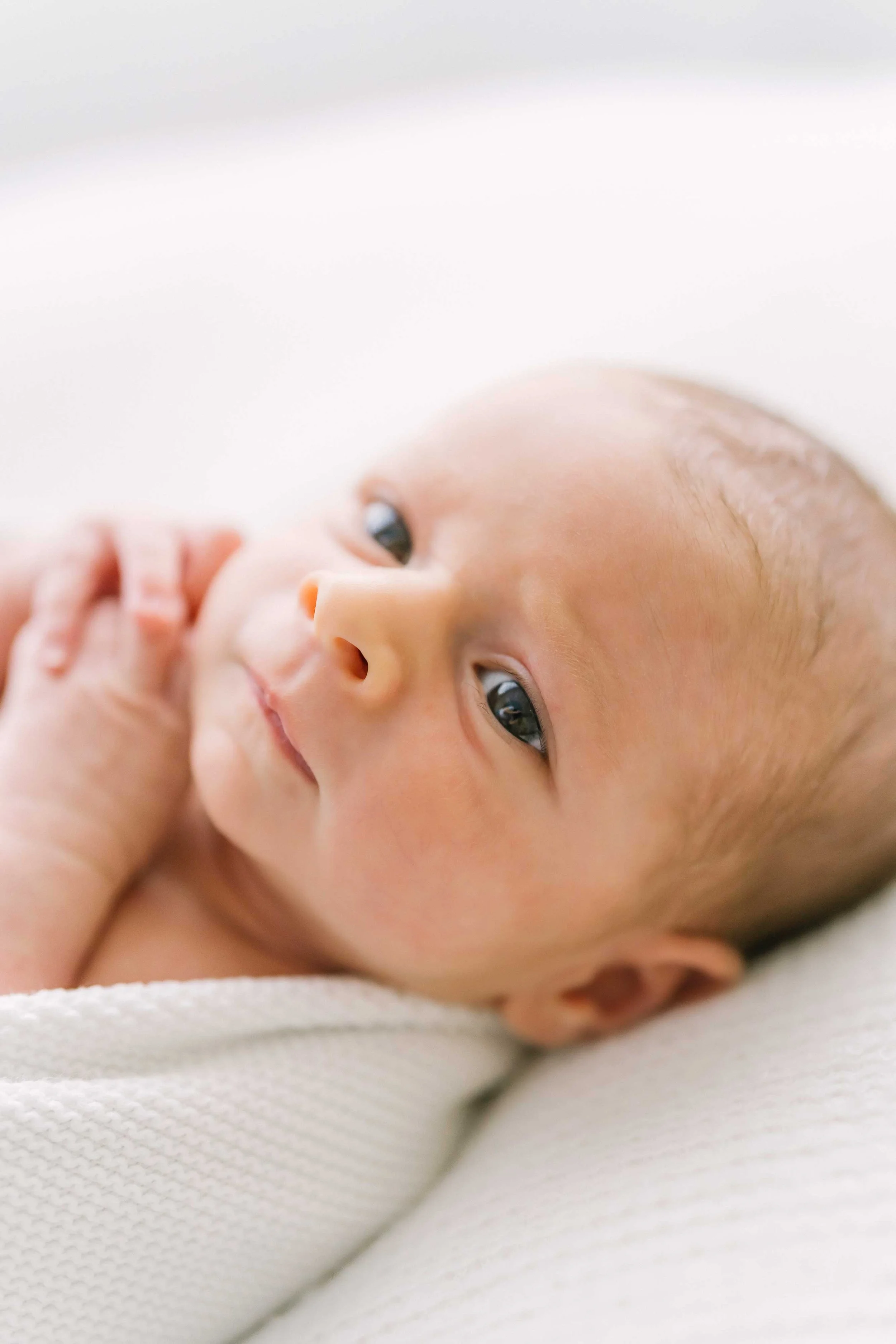 Newborn baby resting on side with hands near face during Grimsby newborn photoshoot