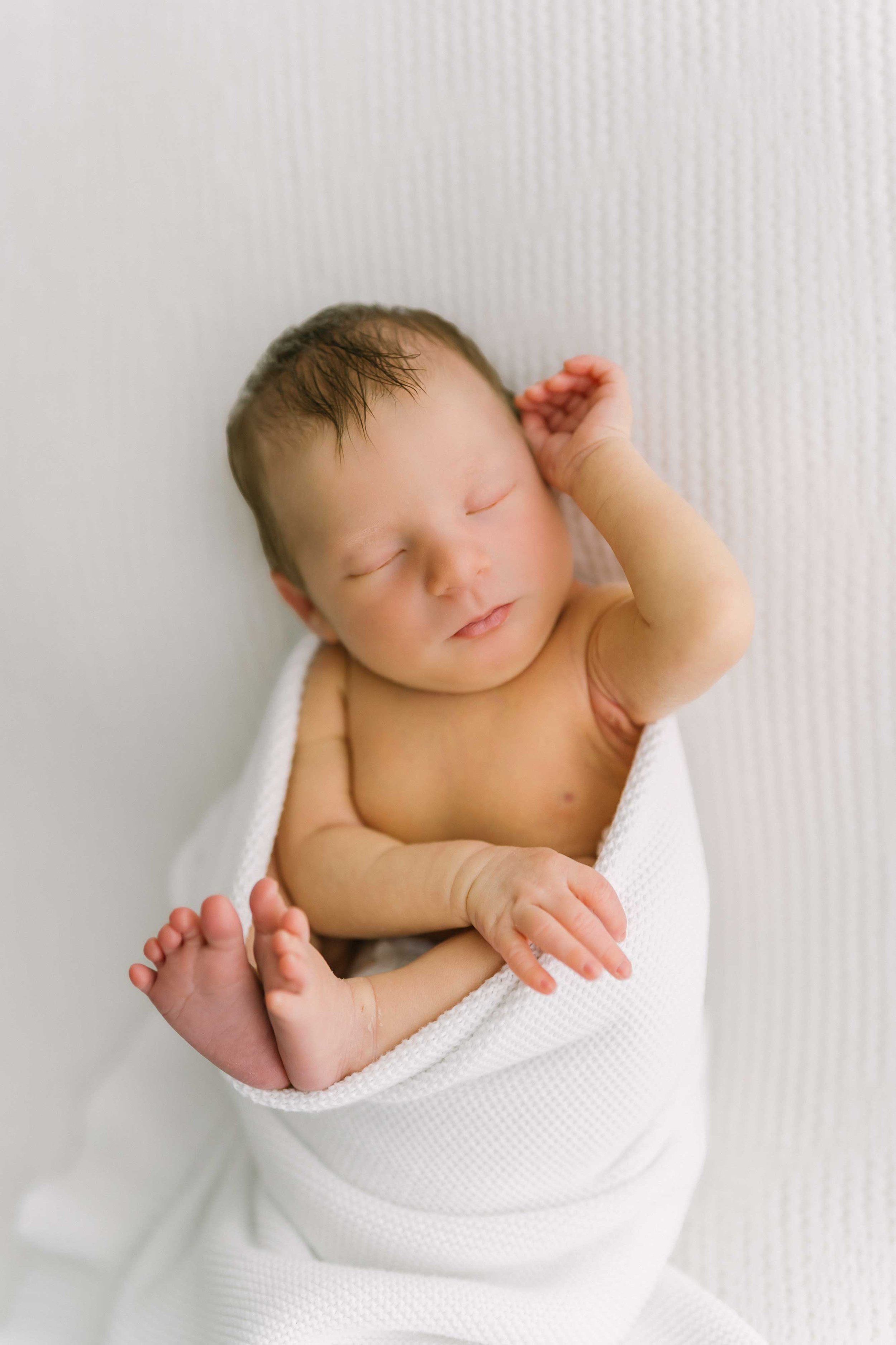 Close-up portrait of a brand new baby with tiny curled fist during newborn photography in Grimsby