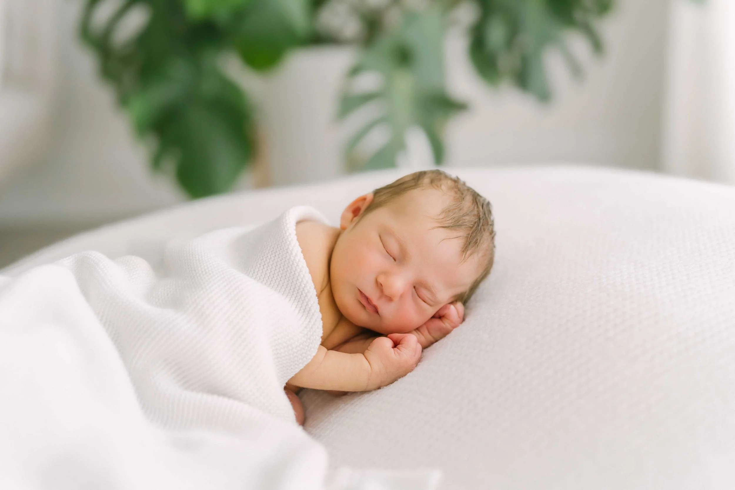 Sleeping newborn stretching one arm out of soft swaddle at Grimsby newborn photography studio