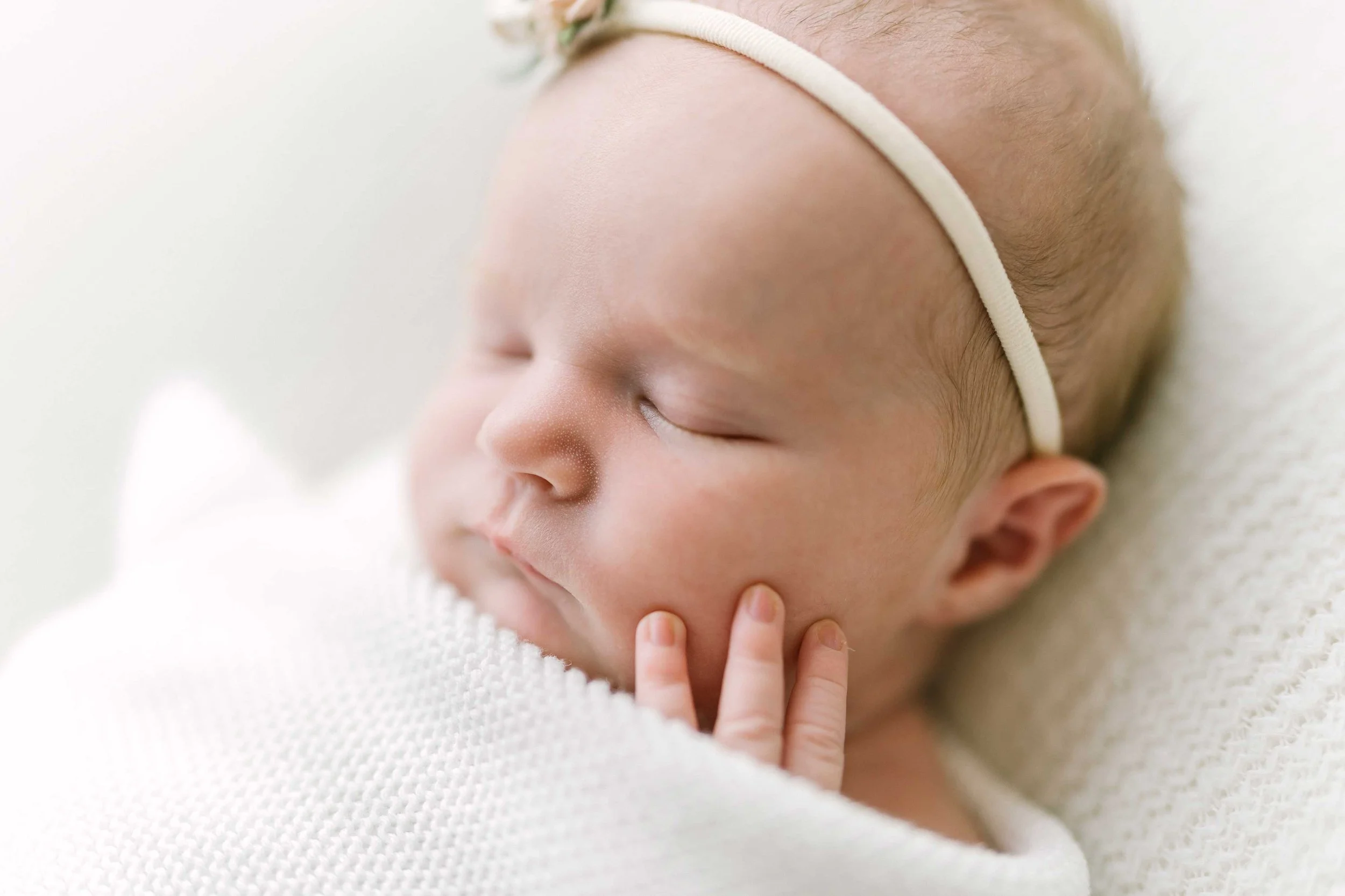 Close-up portrait of newborn baby girl wearing a pink floral headband in Grimsby studio