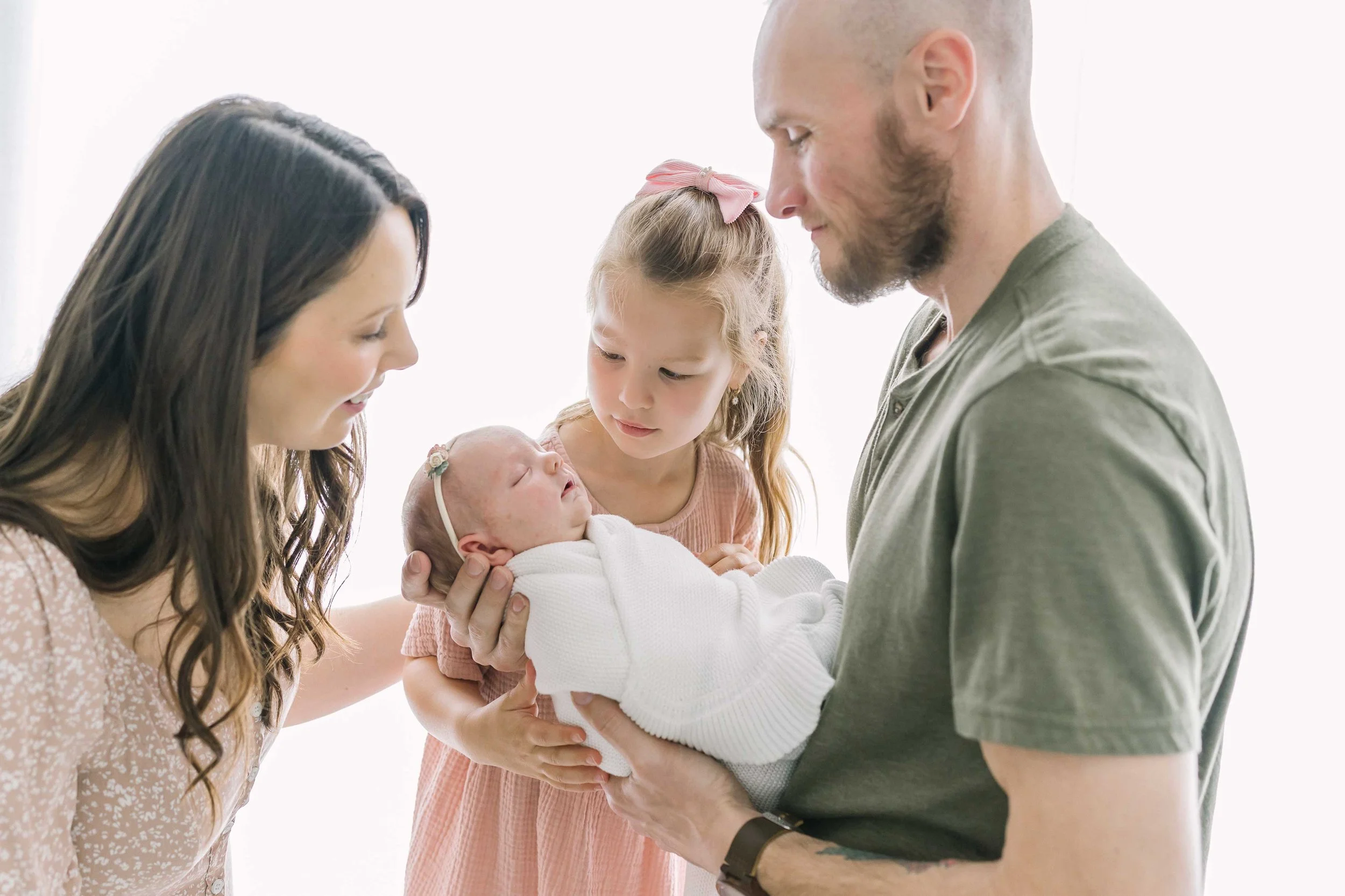 Parents and big sister gathered around newborn baby