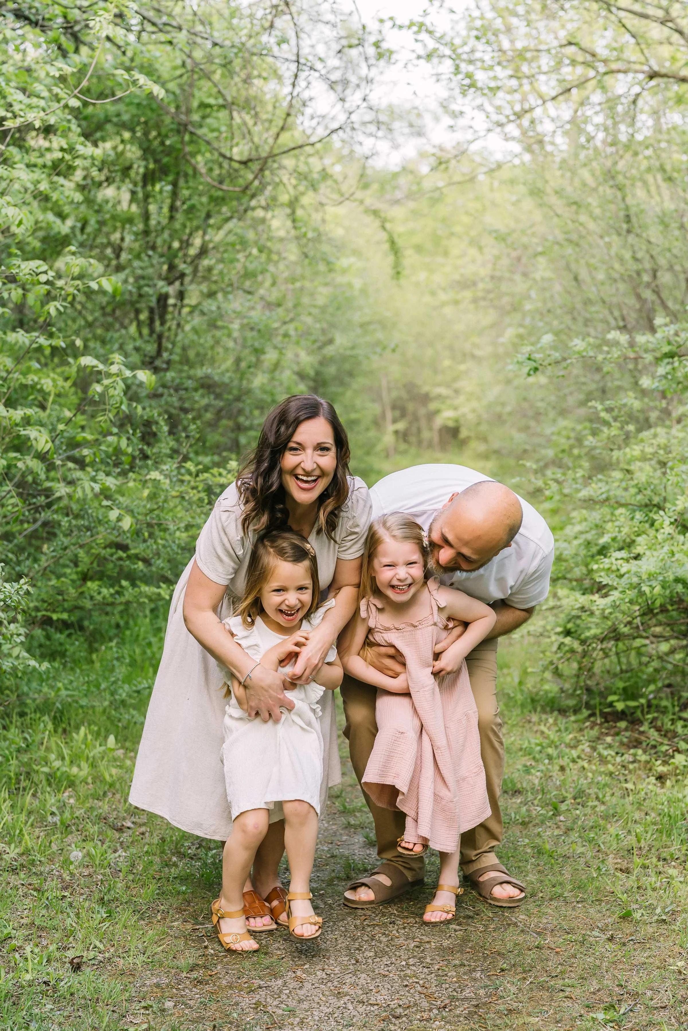 Family laughing together on a wooded trail during an outdoor Niagara family photography session